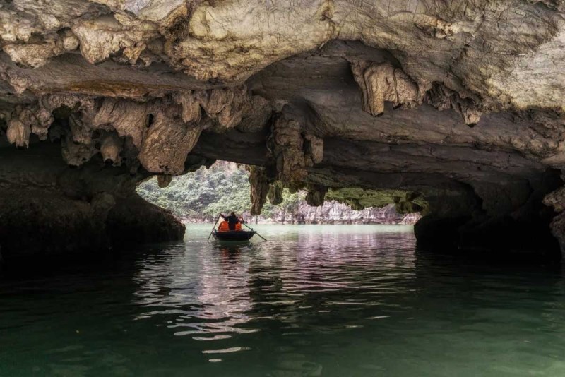 Inside a cave on bamboo boat in Halong Bay Bamboo boat entering the dimly lit interior of a limestone cave in Halong Bay with visible formations