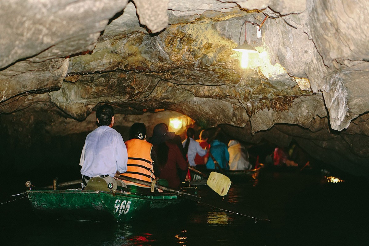 Tourists enjoying a bamboo boat ride through Bright Cave in Lan Ha Bay, surrounded by stunning limestone formations.