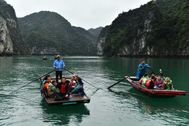 Bamboo Boat Ride Luon Cave Halong Bay calm water scenery Bamboo boat with tourists and rower on calm emerald waters surrounded by limestone cliffs at Luon Cave, Halong Bay
