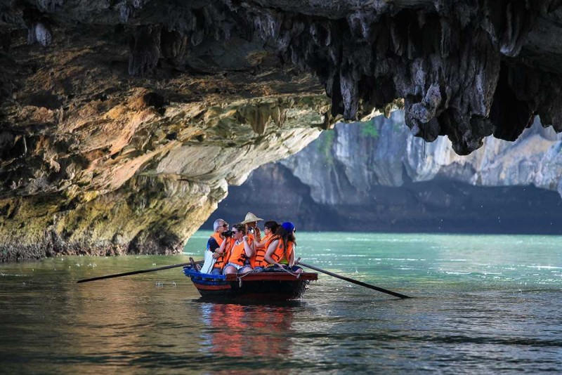 Bamboo Boat Ride Luon Cave Halong Bay entering cave entrance Bamboo boat approaching the entrance of Luon Cave with dense greenery atop limestone cliffs in Halong Bay