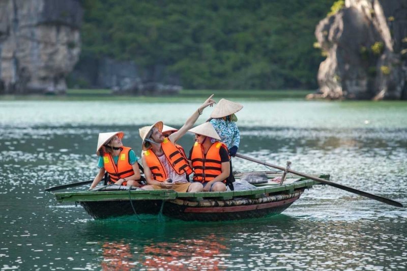 Bamboo Boat Ride Luon Cave Halong Bay under limestone arch Tourists on bamboo boat passing under a large limestone arch at Luon Cave, Halong Bay surrounded by dramatic cliffs