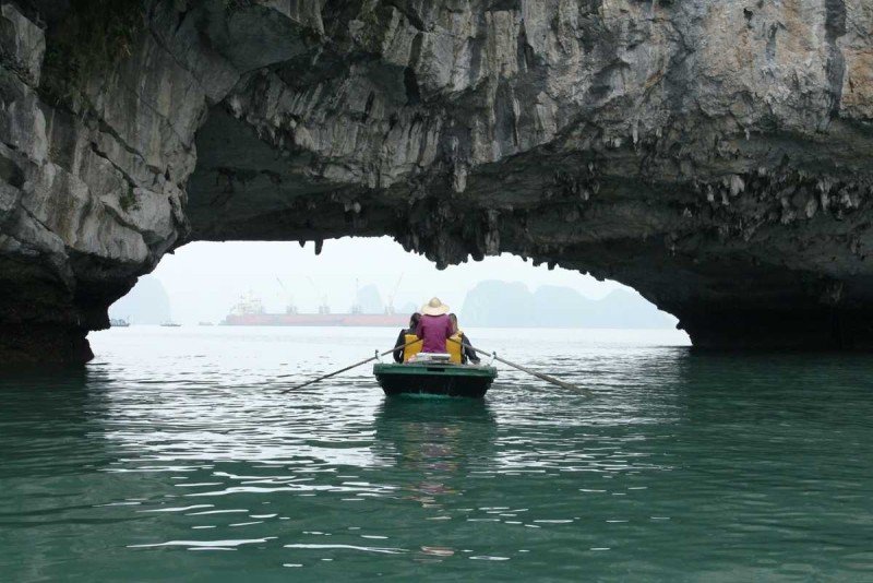 Bamboo Boat Ride Luon Cave Halong Bay multiple boats at cave Several bamboo boats and kayaks gathering near the limestone cave entrance at Luon Cave, Halong Bay