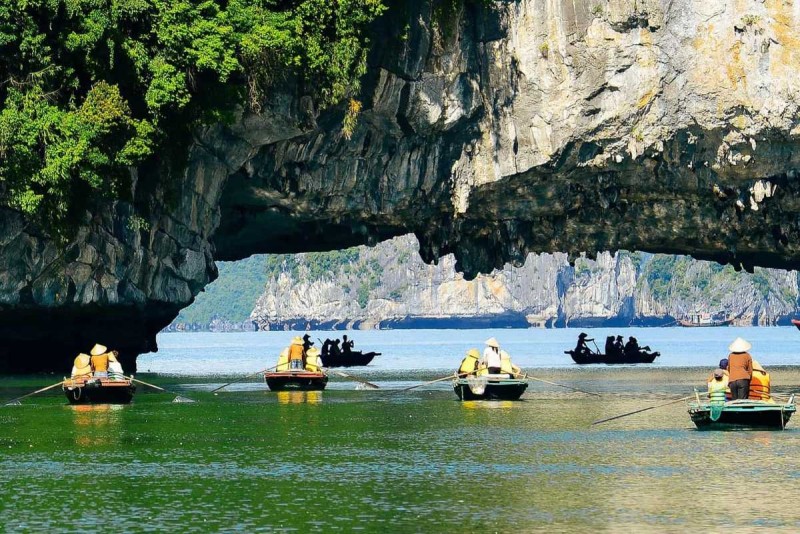 Bamboo Boat Ride Luon Cave Halong Bay tourists pointing cave sights Tourists on bamboo boat wearing life jackets pointing at limestone formations inside Luon Cave, Halong Bay
