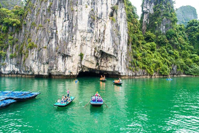 Bamboo Boat Ride Luon Cave Halong Bay traditional boat with tourists Traditional bamboo boat with tourists and a local rower navigating through limestone cliffs at Luon Cave, Halong Bay
