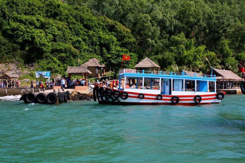 Boat Arrival at Con Se Tre Island Pier Boat docking at the pier of Con Se Tre Island with tourists disembarking amidst lush greenery