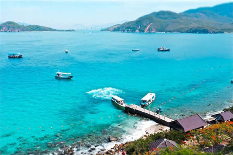 Boat cruise to Mun Island showcasing clear blue tropical waters with boats near the rocky shore