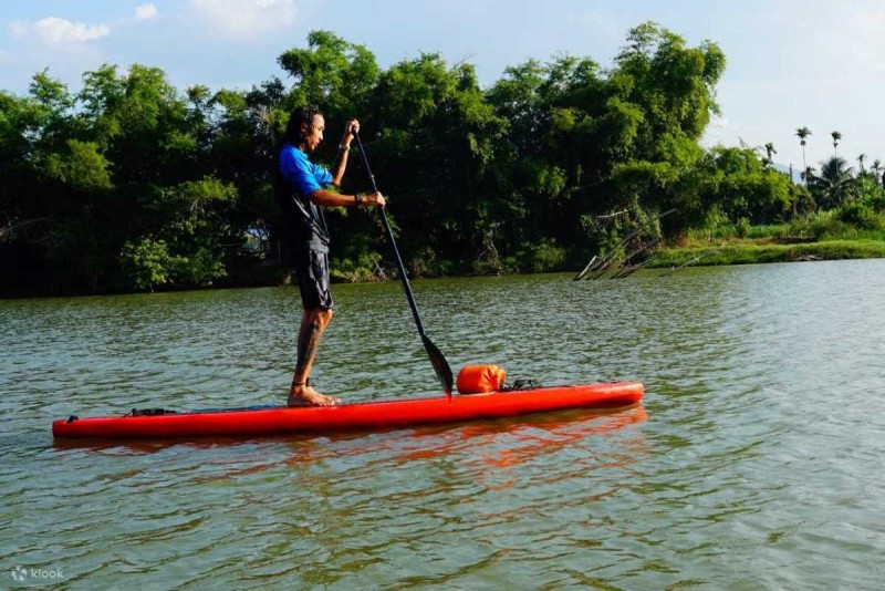 Canoeing Adventure on Cai River Nha Trang Person paddling a red kayak on calm waters of Cai River Nha Trang, highlighting active swimming and water activities