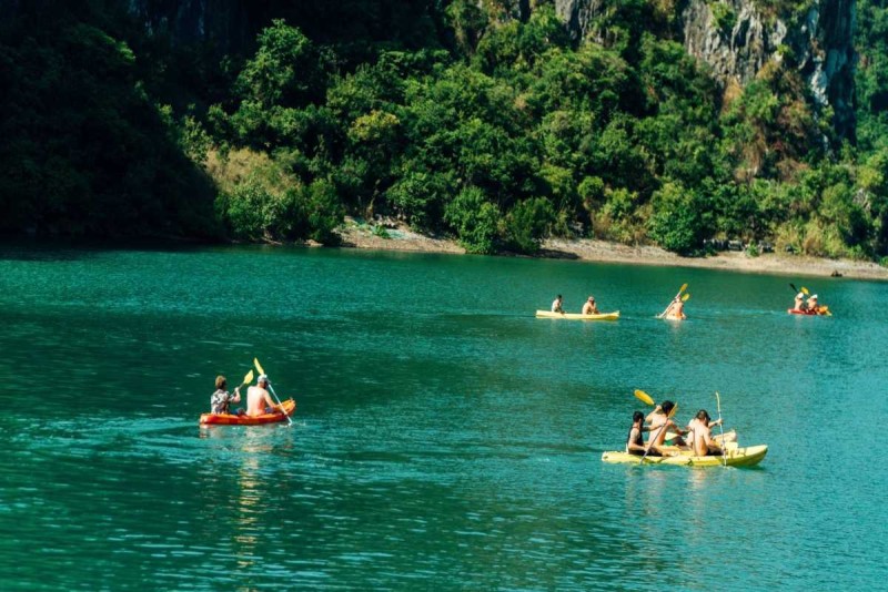 Kayaking Cong Do Island Bai Tu Long Bay clear waters Kayaking Cong Do Island Bai Tu Long Bay captures kayakers on clear green waters with limestone cliffs in the background.