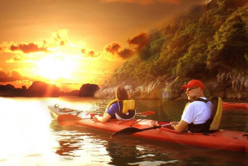 Kayaking Cong Do Island Bai Tu Long Bay vibrant orange kayak tour Kayaking Cong Do Island Bai Tu Long Bay features tourists paddling vibrant orange kayaks among towering limestone cliffs.
