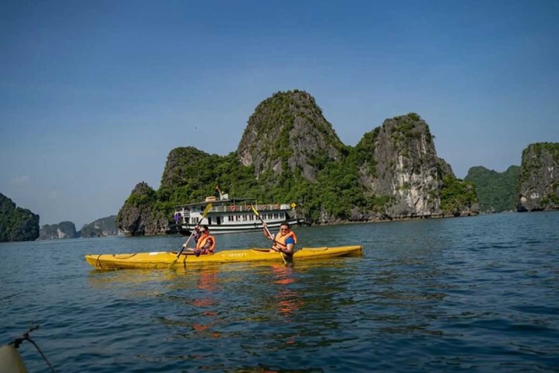 Kayaking Cong Do Island Bai Tu Long Bay scenic paddling Kayaking Cong Do Island Bai Tu Long Bay shows two paddlers enjoying a yellow kayak with limestone cliffs in the background.