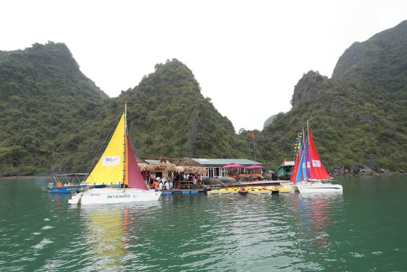 Kayaking Cong Do Island Bai Tu Long Bay bright sunny day paddling Kayaking Cong Do Island Bai Tu Long Bay shows kayakers enjoying a bright sunny day with clear blue skies and lush limestone formations.