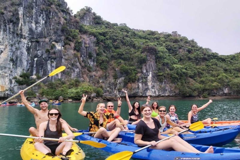 Kayaking Cua Van Halong Bay scenic village surrounded by karsts Kayaking Cua Van Halong Bay showing floating houses nestled between limestone karsts under a partly cloudy sky