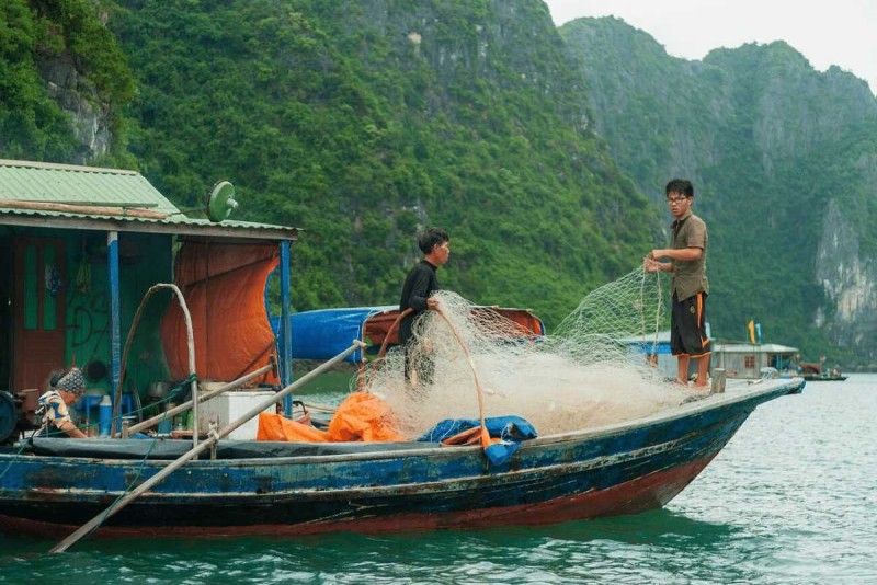 Kayaking Cua Van Halong Bay tourists exploring karsts passage Kayaking Cua Van Halong Bay tourists navigating through limestone karsts with life jackets on sunny day