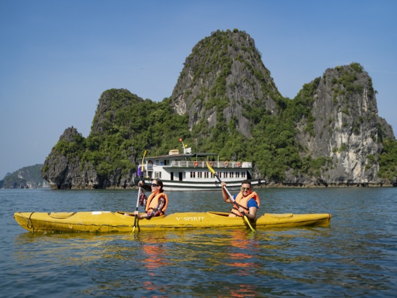 Tourists kayaking through calm waters of Halong Bay’s secluded area.