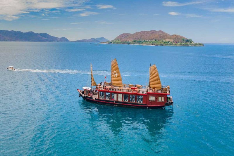 Traditional Junk Boat Cruise at Hon Mot Island Nha Trang Classic wooden junk boat sailing near Hon Mot Island in the clear blue waters of Nha Trang Bay