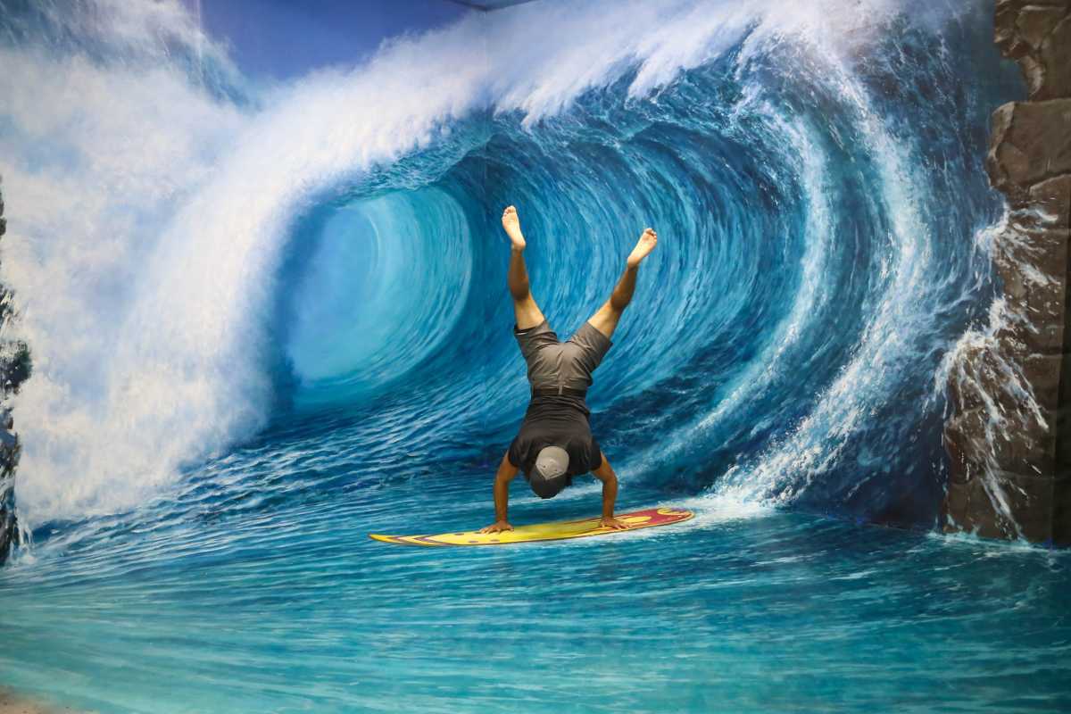 3D Museum Art in Paradise Da Nang surfing adventure wave mural 3D Museum Art in Paradise Da Nang showcases a visitor posing on a surfboard in front of a large 3D wave mural in the adventure zone.