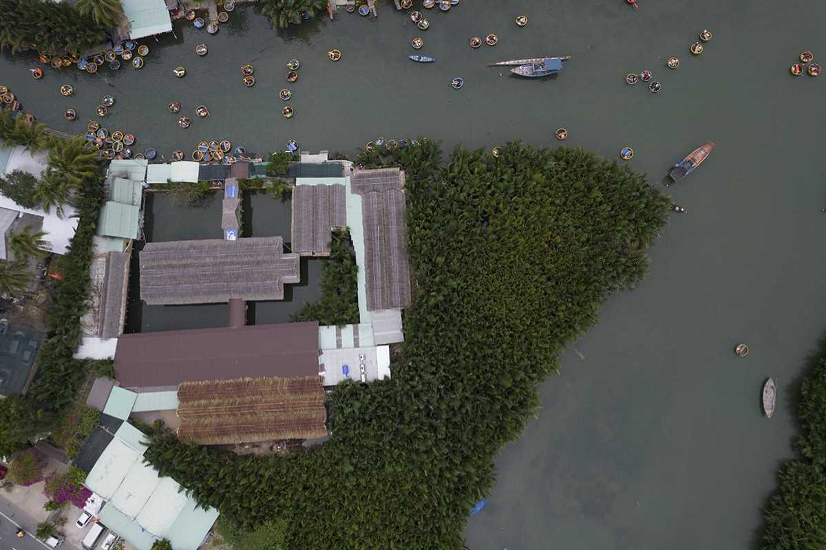 Aerial View of Basket Boats and Coconut Groves Aerial shot showing basket boats navigating water channels surrounded by coconut trees in Cam Thanh Village