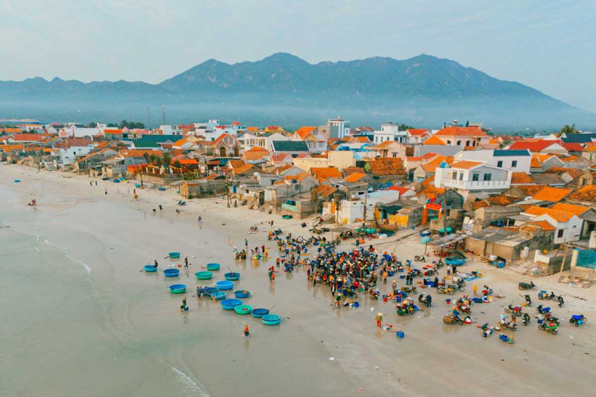 Aerial view of Ninh Thuy Fishing Village with coastal homes and beach Aerial view showing coastal homes, sandy beach, and fishing boats in Ninh Thuy Fishing Village