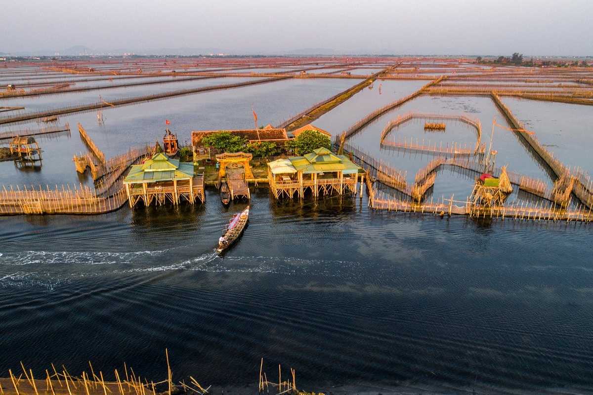 Aerial View of Tam Giang Lagoon with Boats and Mangroves Aerial shot showing wooden boats, mangrove patches, and fishing activities on Tam Giang Lagoon