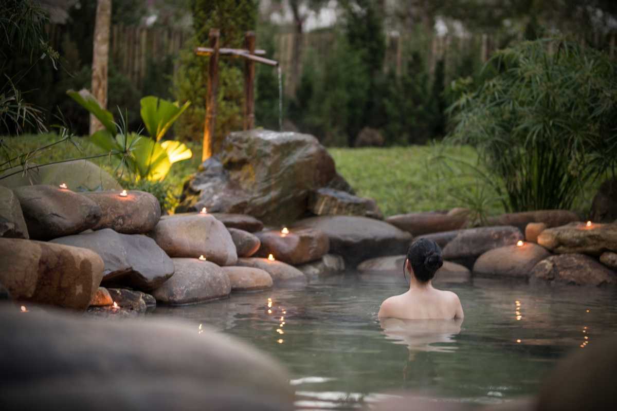 Evening Hot Spring Pool Ambiance at Alba Thanh Tan Woman soaking in hot spring pool under warm evening lighting at Alba Thanh Tan Hot Springs