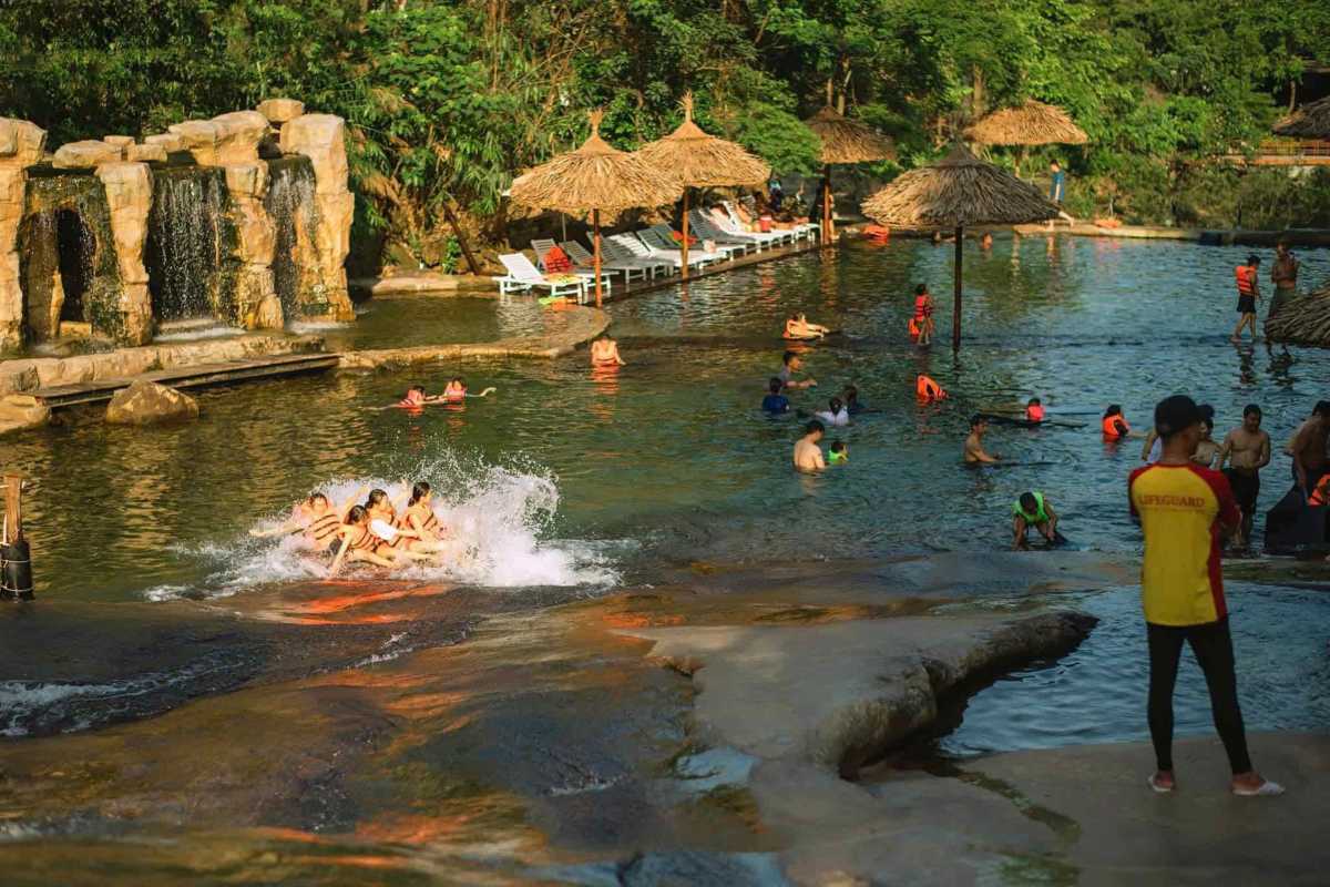 Family-Friendly Hot Spring Pool at Alba Thanh Tan Visitors swimming and playing in large natural hot spring pool with shaded areas at Alba Thanh Tan