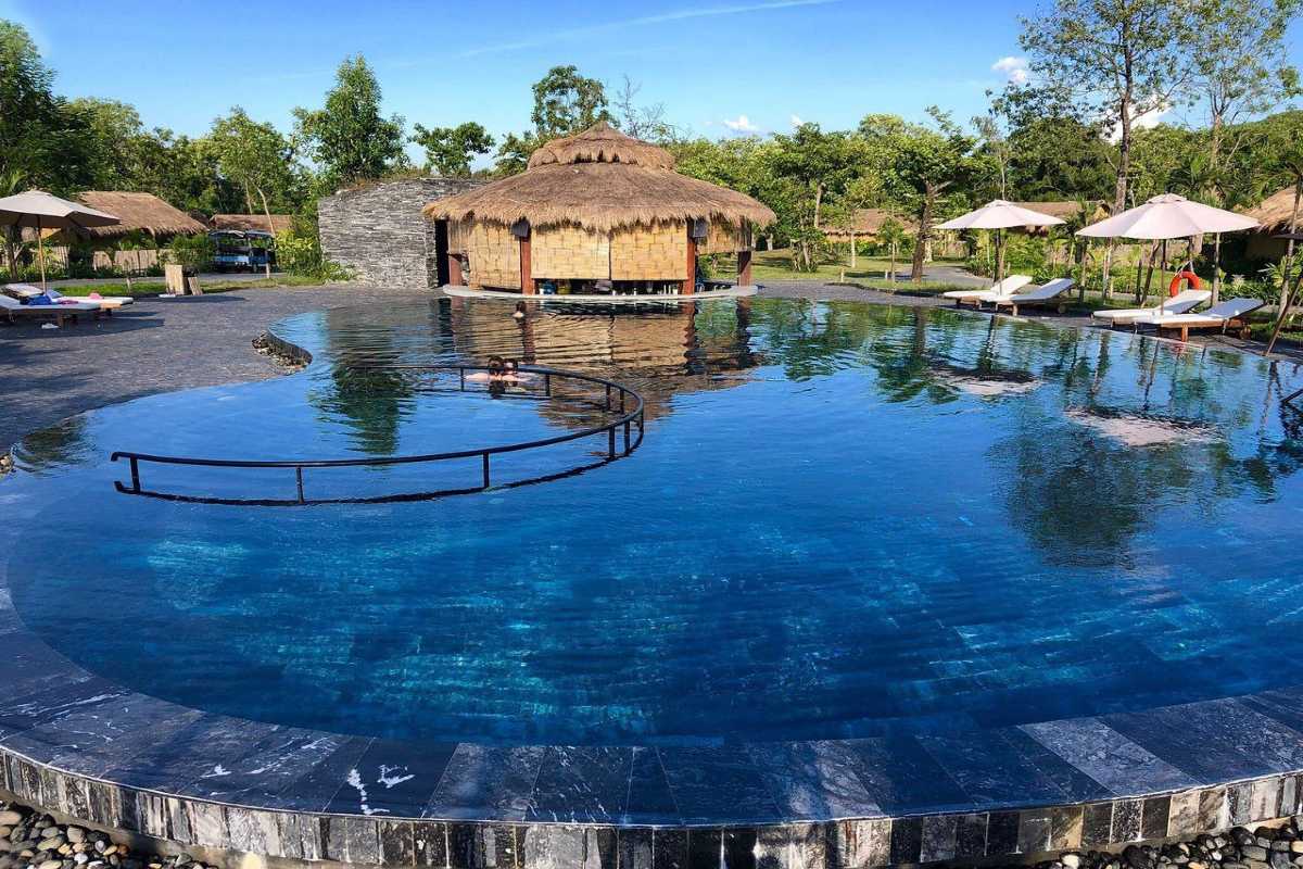 Infinity Pool and Thatched Roof Pavilion Infinity pool with clear water and a thatched roof pavilion surrounded by greenery at Alba Thanh Tan