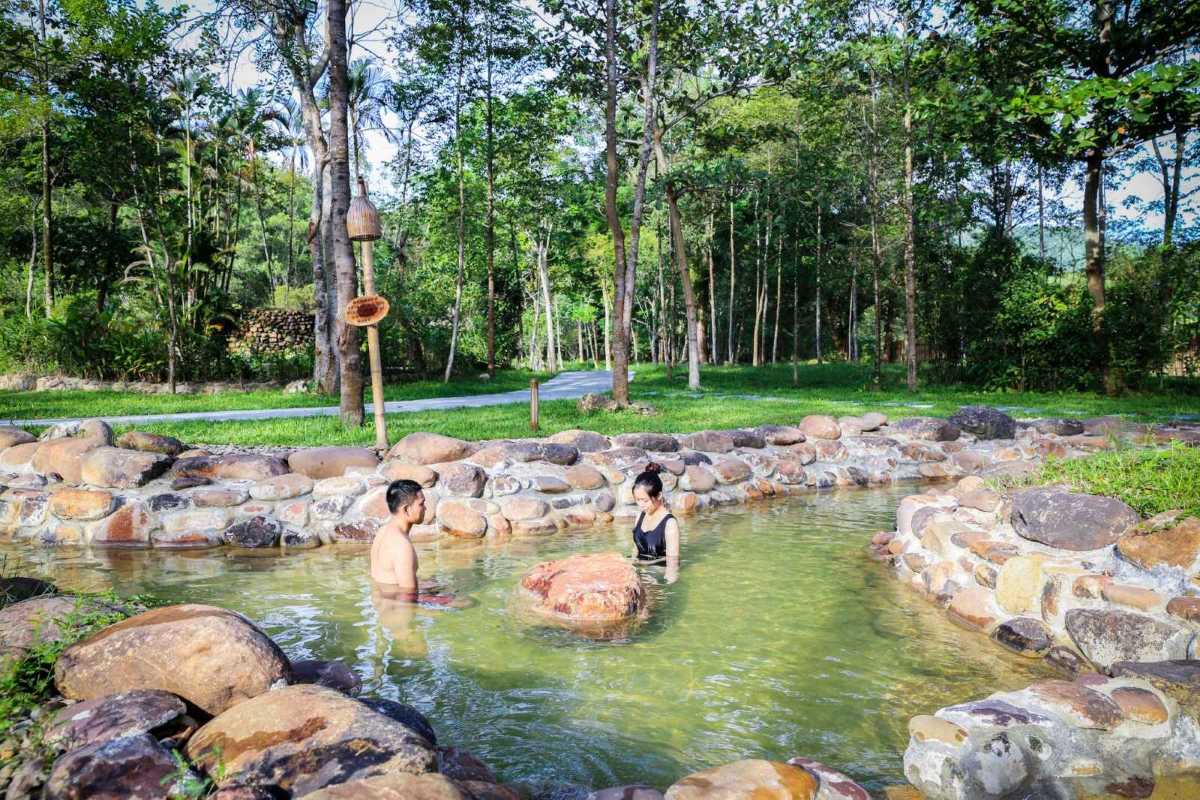 Outdoor Hot Spring Bath Surrounded by Trees Couple enjoying outdoor hot spring bath surrounded by trees and natural stones at Alba Thanh Tan