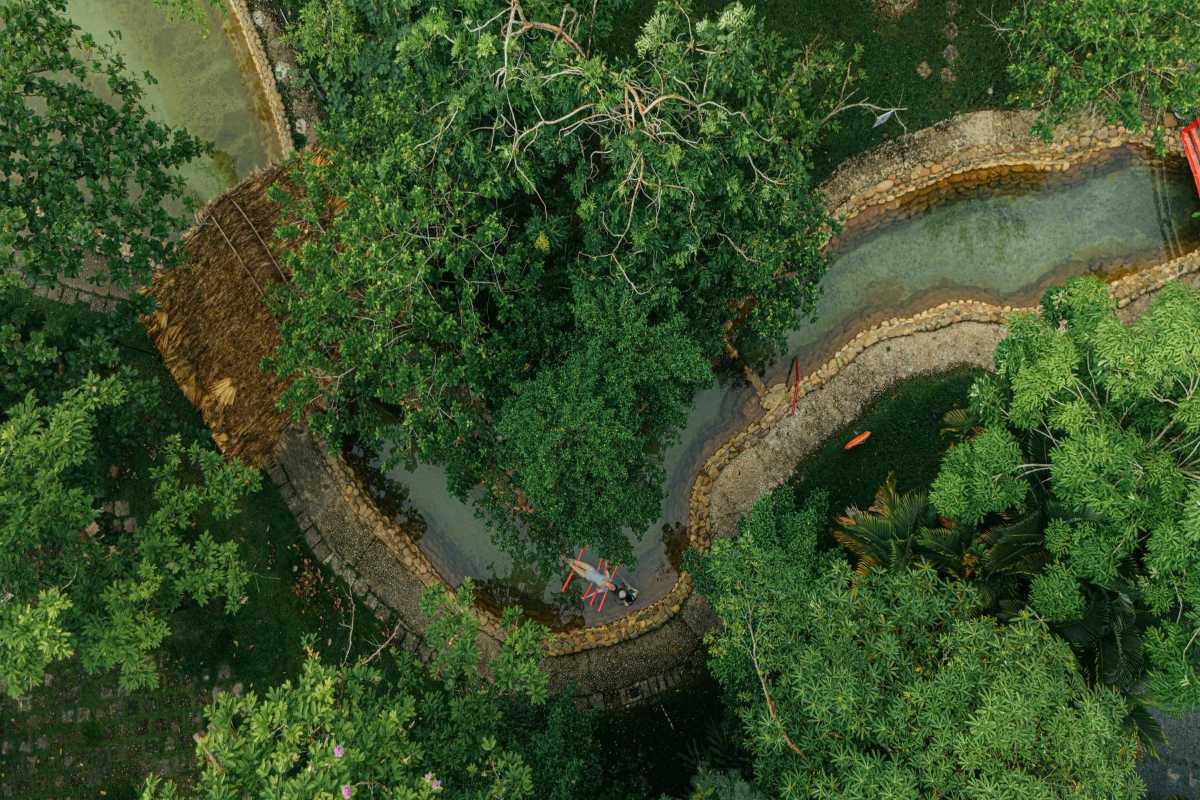 Overhead View of Hot Spring River and Huts Aerial photo of hot spring river with small thatched huts nestled among dense trees at Alba Thanh Tan