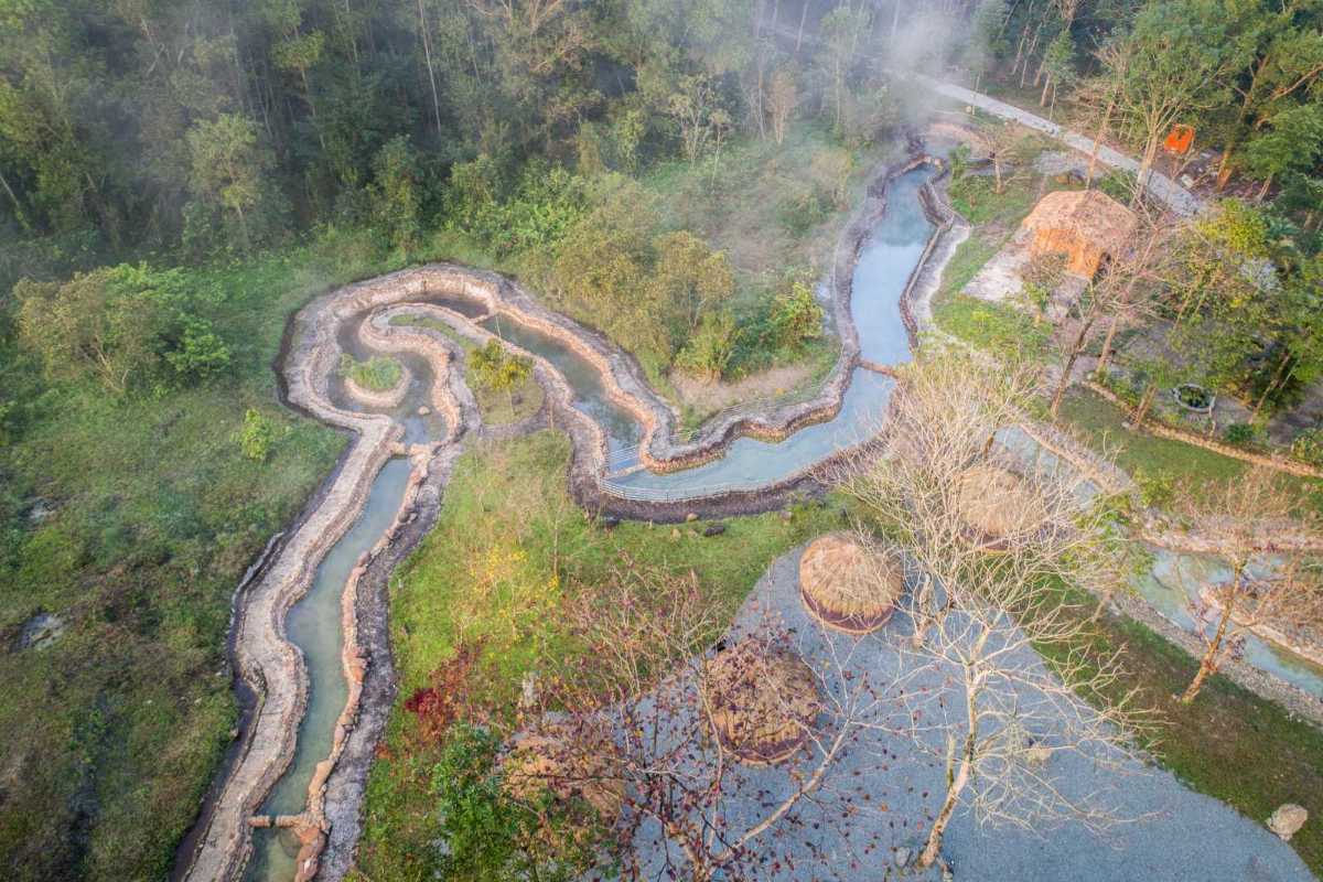 Winding Hot Spring River Through Forest Top view of a winding hot spring river flowing through dense forest at Alba Thanh Tan Hot Springs