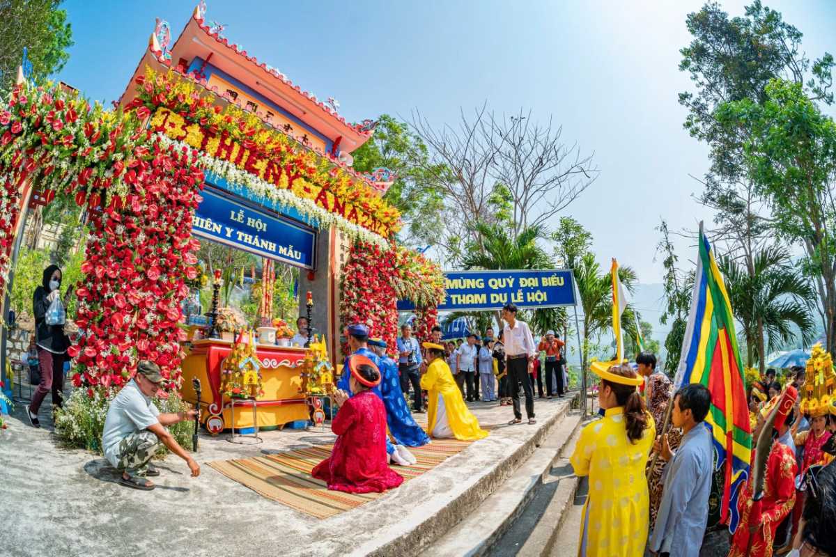 Kneeling ritual at floral altar gate Worshippers kneel in prayer at the flower-decorated gate of Am Chua Temple during a daytime ceremony.