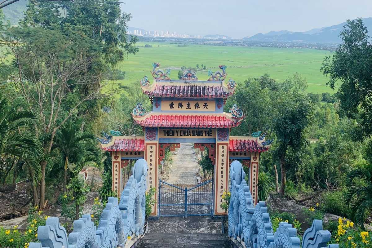 Am Chua Temple hillside gate view Looking down from Am Chua Temple gate across green rice fields and distant city skyline.