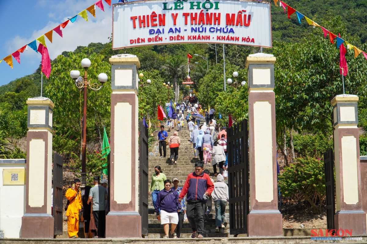 Main pilgrimage gate to Am Chua Temple Entrance gate to Am Chua Temple with pilgrims climbing steps under banners and colorful flags.