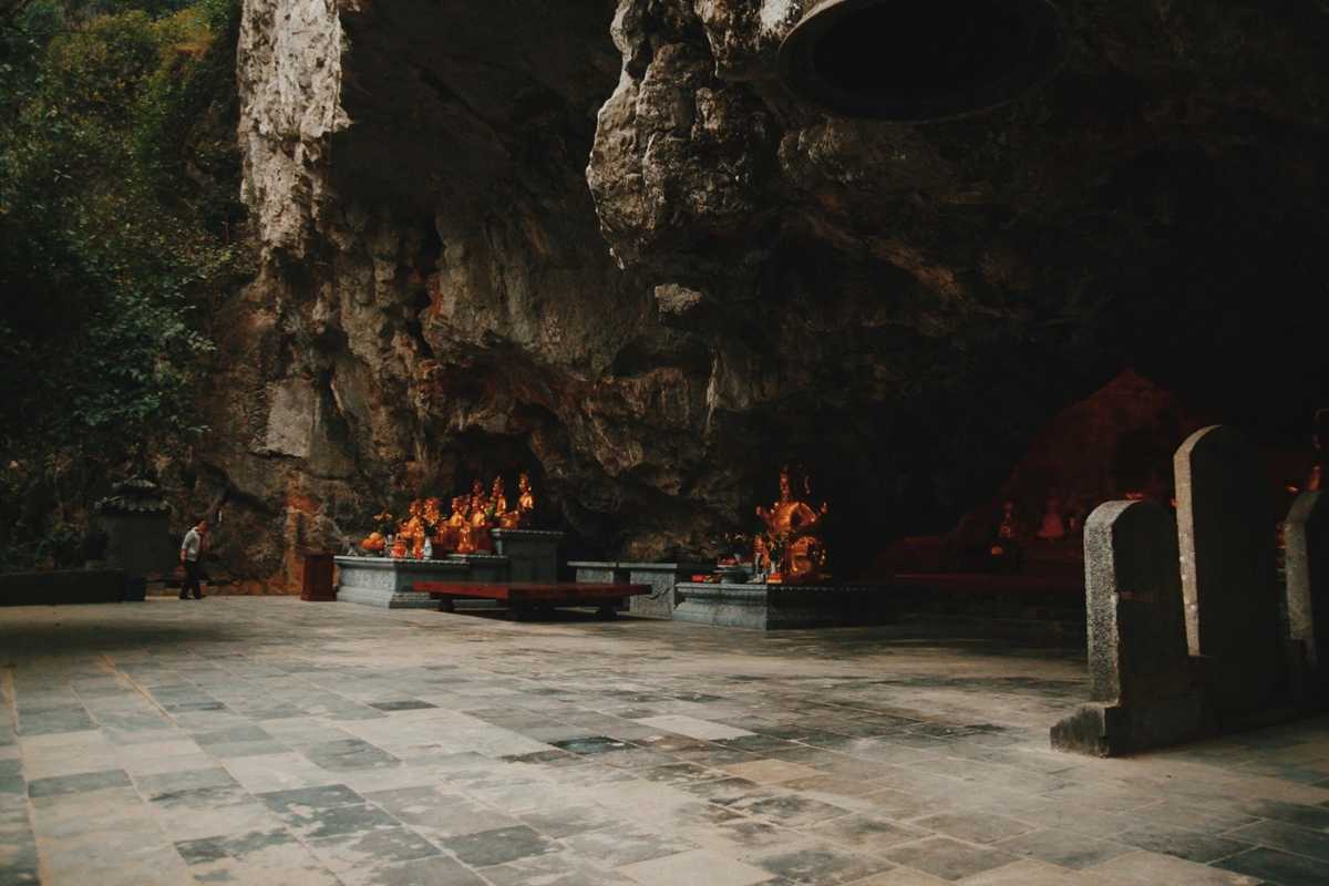 Am Tien Cave Ninh Binh sacred cave shrine interior Am Tien Cave Ninh Binh shrine interior with golden statues and ancient altars carved in the cave wall.