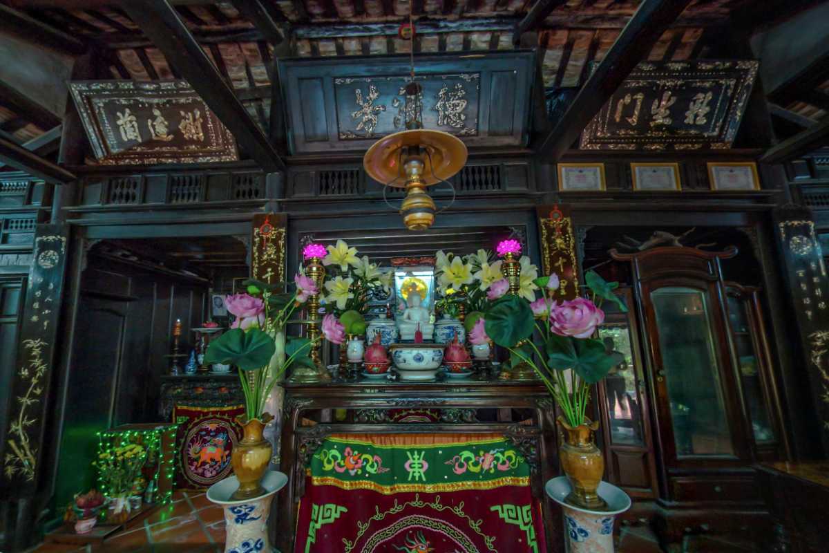 Traditional family altar inside Phu Vinh home Colorful family altar with lotus flowers and wood carvings inside Phu Vinh Ancient Village home