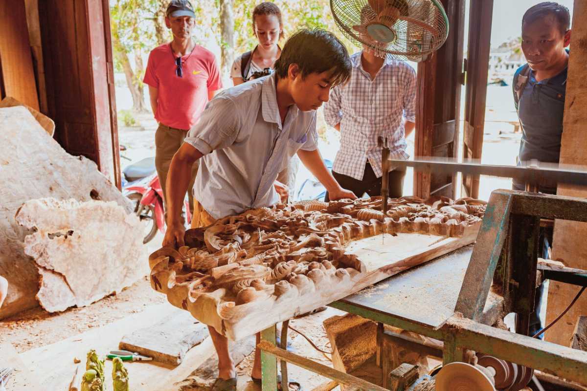 Artisans Carving Wood Inside Workshop Artisan carving a detailed wooden sculpture inside a workshop at Kim Bong Carpentry Village