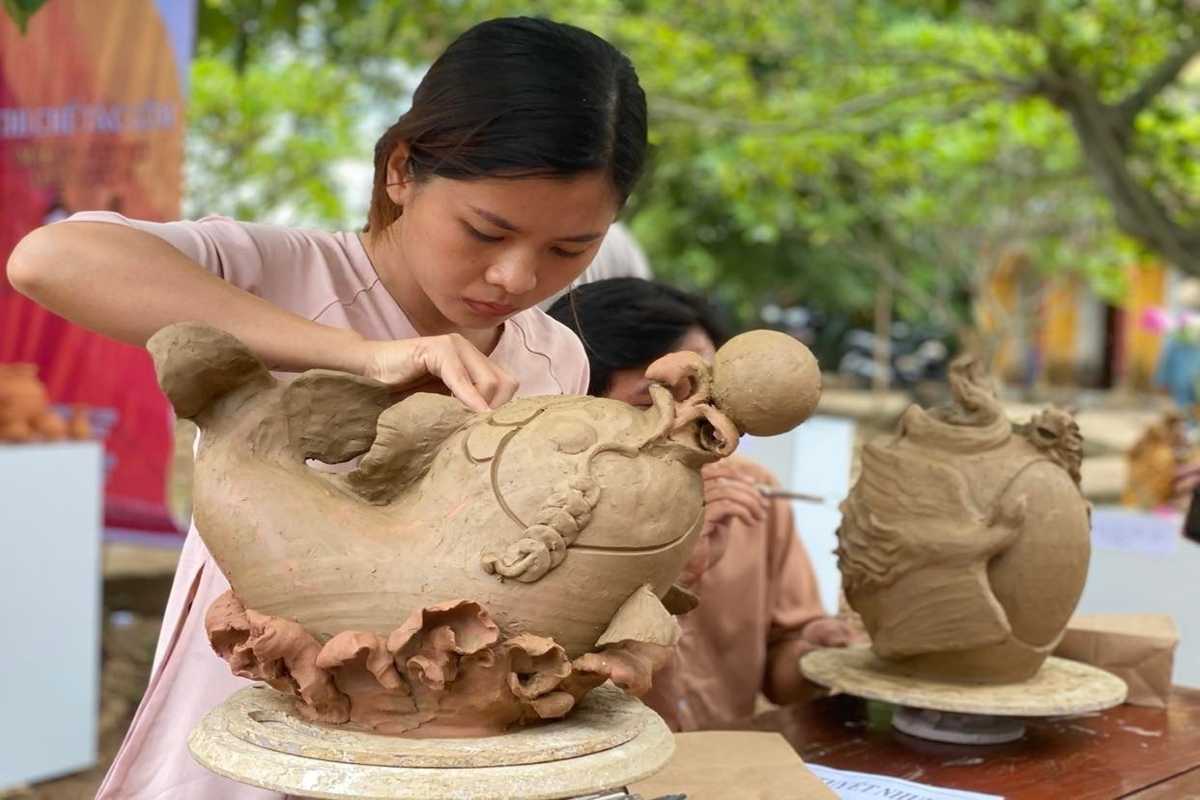 Artisan Sculpting Clay Pottery at Thanh Ha Village Female artisan carefully sculpting intricate clay pottery details by hand at Thanh Ha Pottery Village