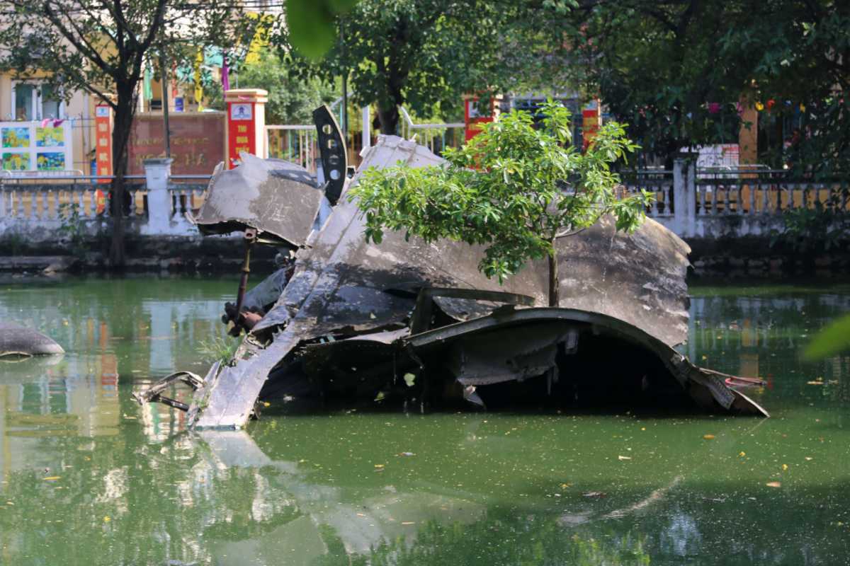 B-52 Plane Remains at Huu Tiep Lake Hanoi B-52 plane remains partially submerged in Huu Tiep Lake Hanoi surrounded by green water and urban buildings