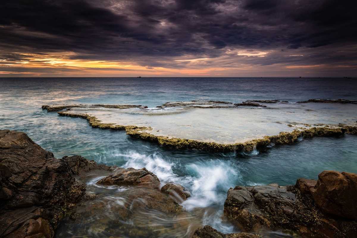Ba Dien Beach Sunset View Sunset over Ba Dien Beach with waves crashing on rocks in Ninh Thuan