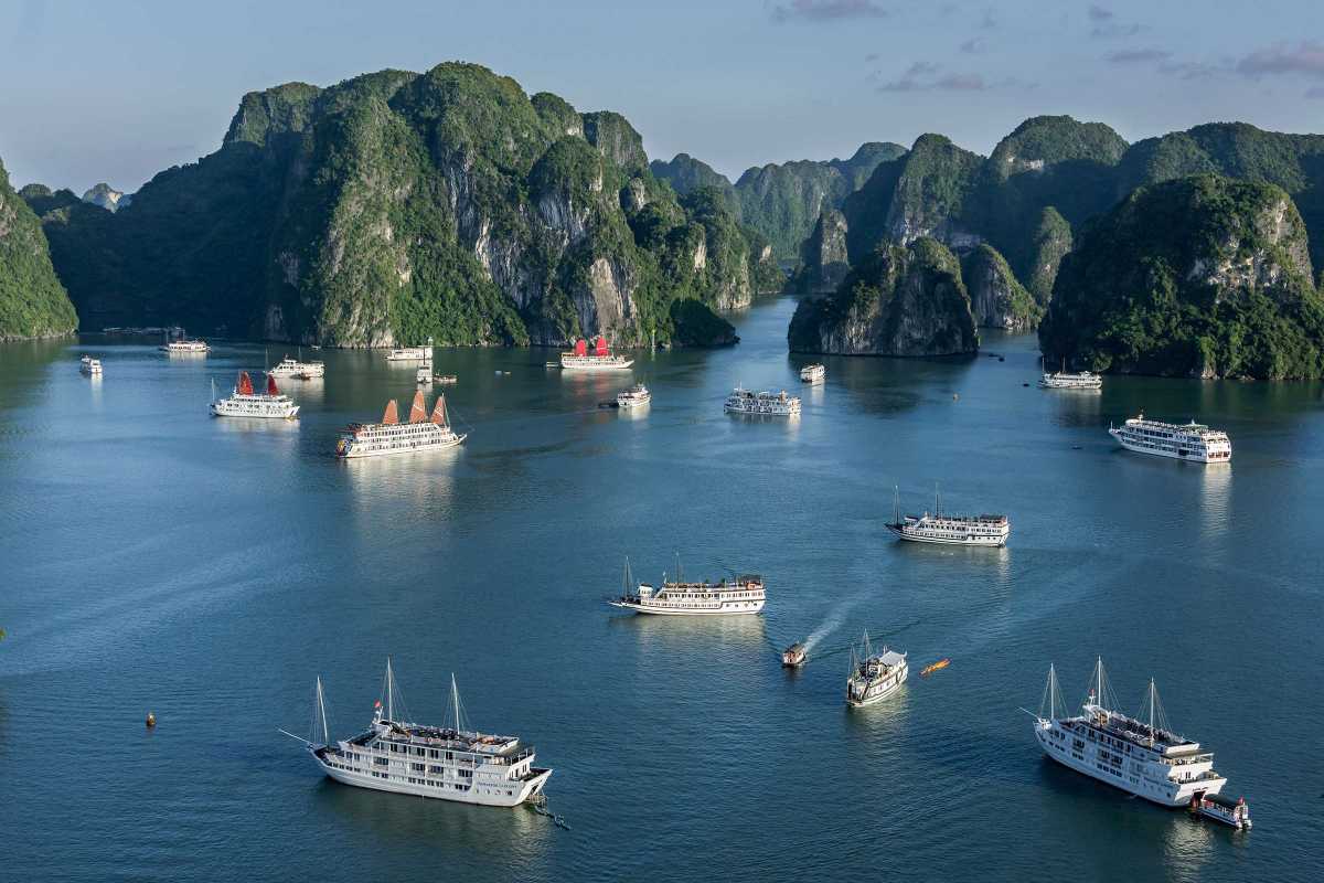 Ba Ham Lake Halong Bay scenic cruise with multiple boats Scenic cruise on Ba Ham Lake Halong Bay showing multiple traditional and modern boats among karst islands.