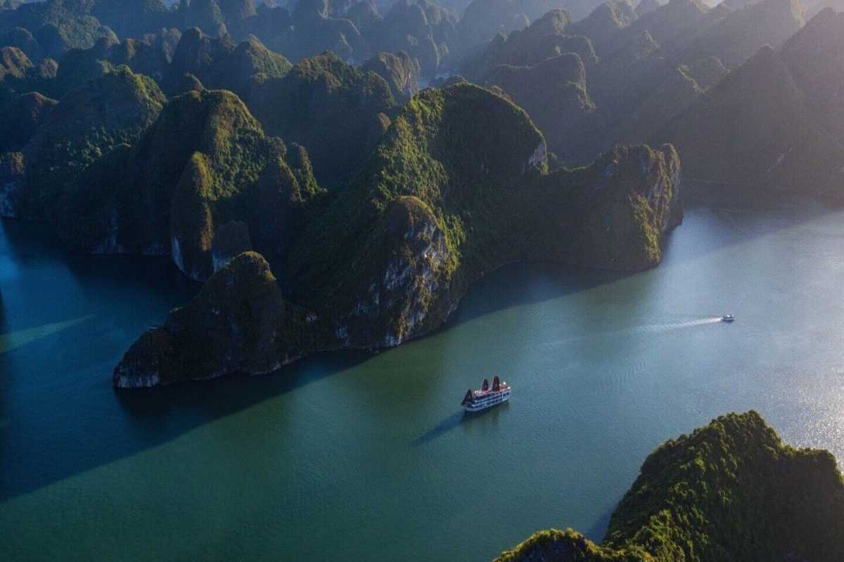 Ba Ham Lake Halong Bay traditional boat cruising waters Traditional wooden boat cruising the calm waters of Ba Ham Lake Halong Bay framed by towering limestone islands.