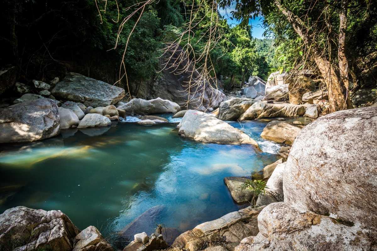 Jungle pool at Ba Ho Waterfalls Blue-green pool at Ba Ho Waterfalls with large smooth rocks and forest shadows.