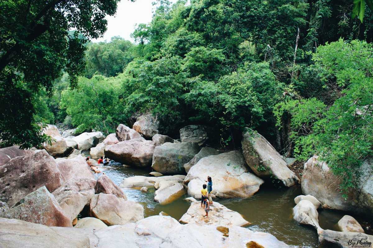 Exploring Ba Ho jungle river Travelers walk over river stones in the lush jungle section of Ba Ho Waterfalls.