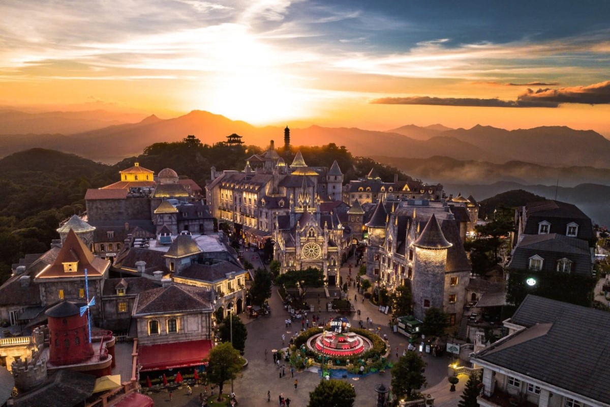 Aerial view of Ba Na Hills French Village at sunset, featuring European-style buildings and the vibrant central square.