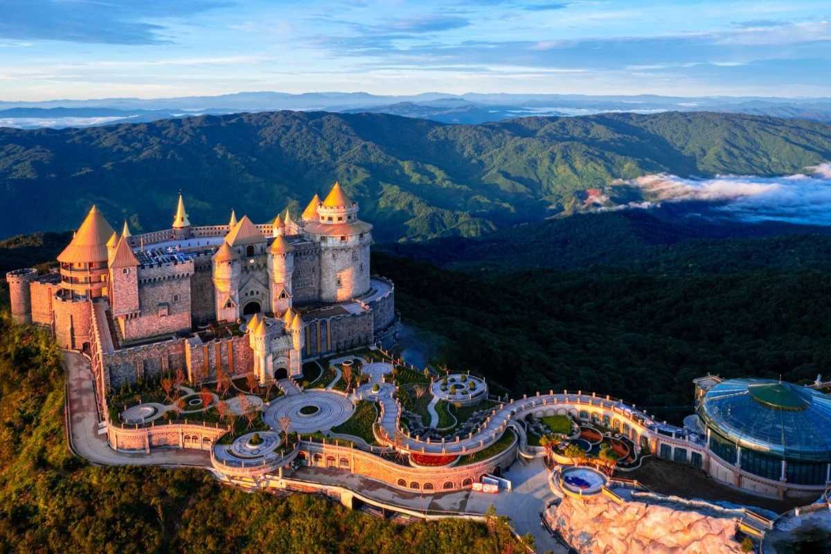 Ba Na Hills French Village castle sunrise with mountain backdrop French Village castle at Ba Na Hills illuminated by sunrise, surrounded by mountain scenery and forest