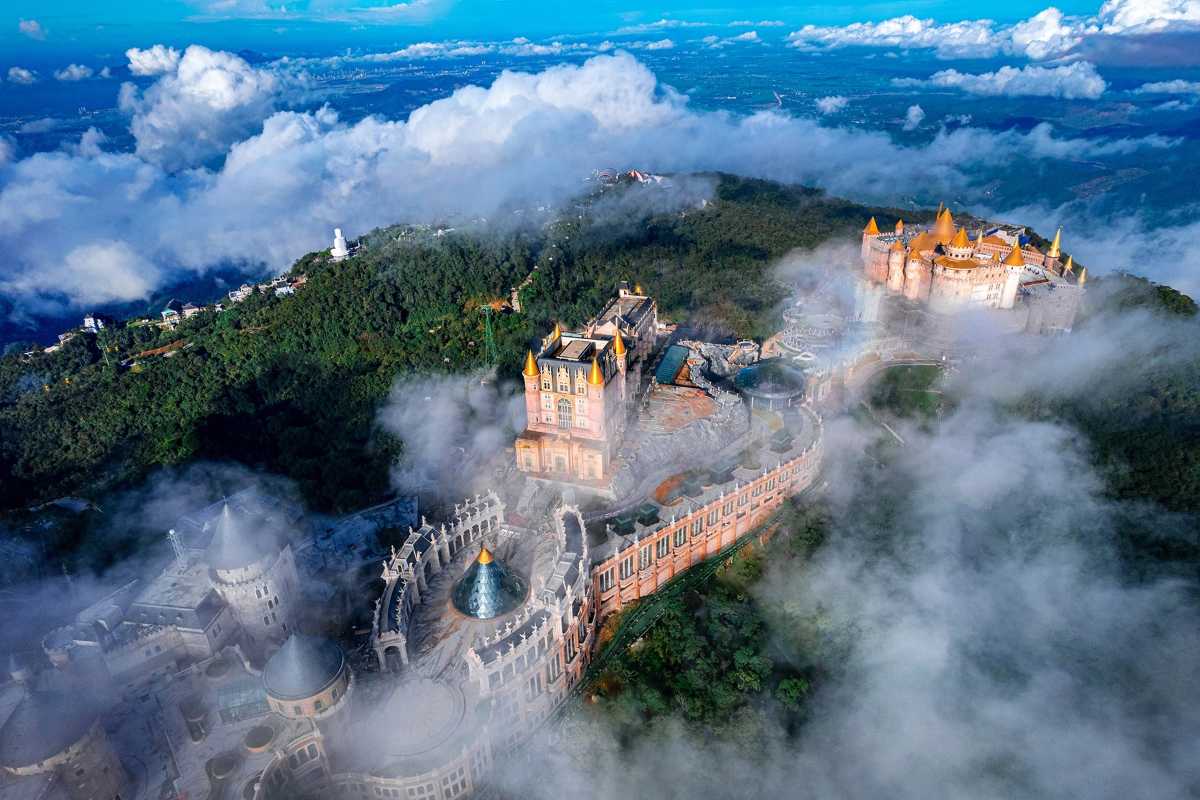 Ba Na Hills French Village castle misty morning panoramic scene Mist-shrouded French Village castle at Ba Na Hills, with dramatic mountain ridges and clouds in early morning