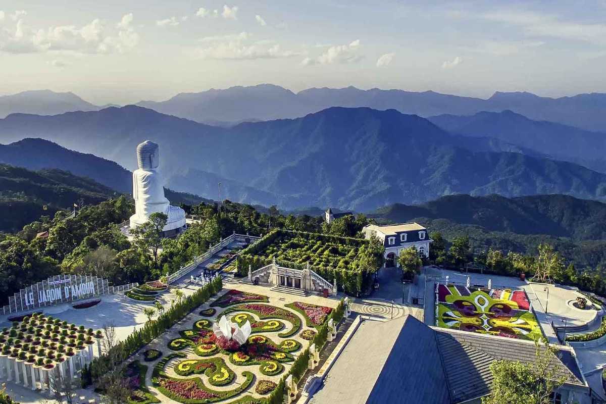 Ba Na Hills Le Jardin D’Amour gardens Buddha statue mountain Le Jardin D’Amour flower gardens at Ba Na Hills with large white Buddha statue overlooking misty mountain range