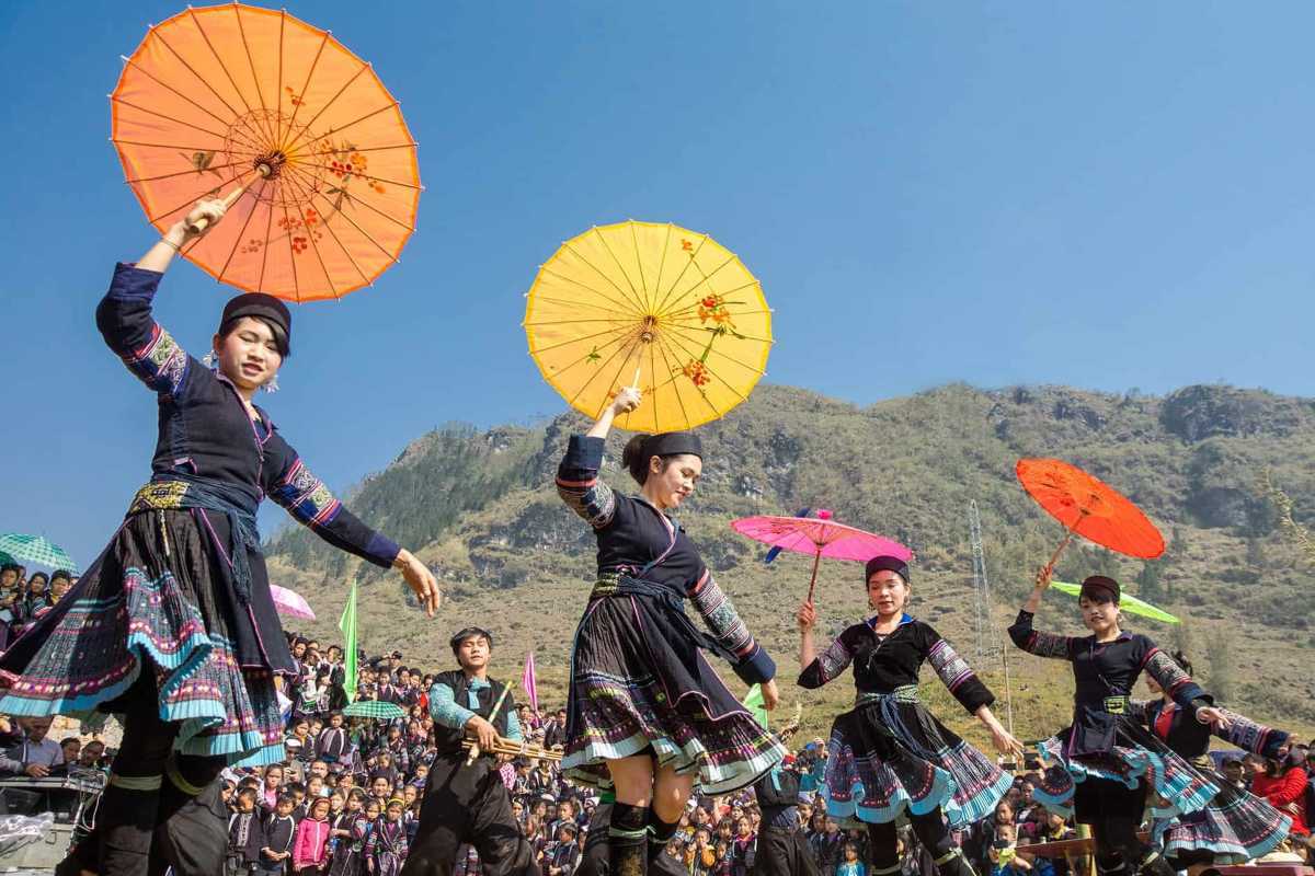 Bac Ha Market Sapa ethnic umbrella dance festival performance Bac Ha Market festival with ethnic dancers holding colorful umbrellas, traditional costumes, and mountain background