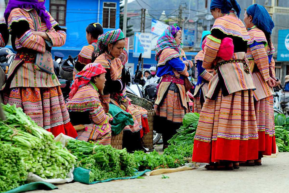 Bac Ha Market Sapa ethnic women trading greens and herbs Bac Ha Market group of ethnic women selling fresh herbs, greens, and vegetables on market steps in traditional dress