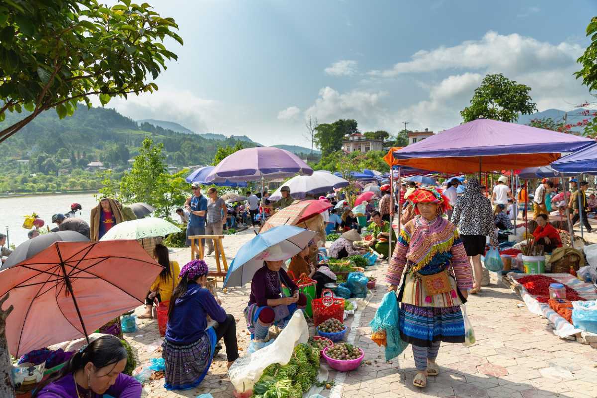 Bac Ha Market Sapa open air riverside market gathering Bac Ha Market riverside market view with colorful umbrellas, ethnic vendors, fresh vegetables, and scenic highland backdrop