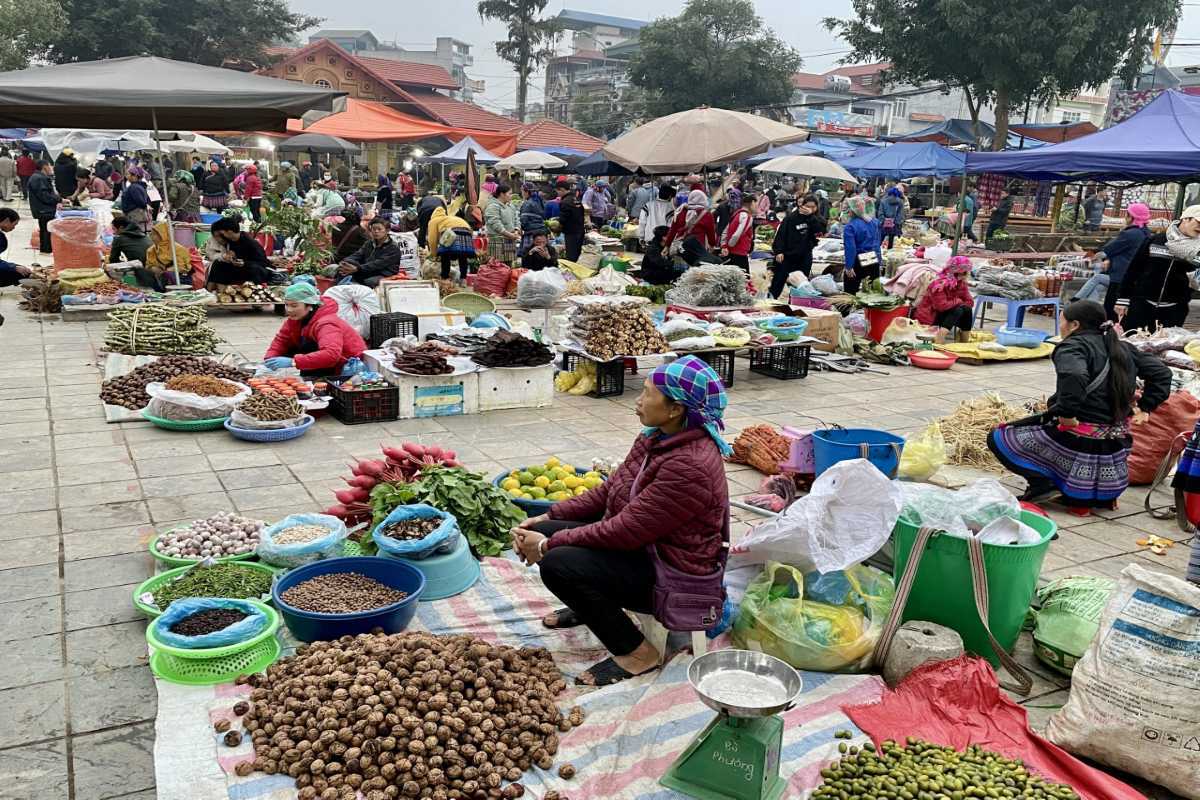 Bac Ha Market Sapa open-air square with diverse market stalls Bac Ha Market open square lined with market stalls, fresh produce, herbs, and ethnic women selling regional goods